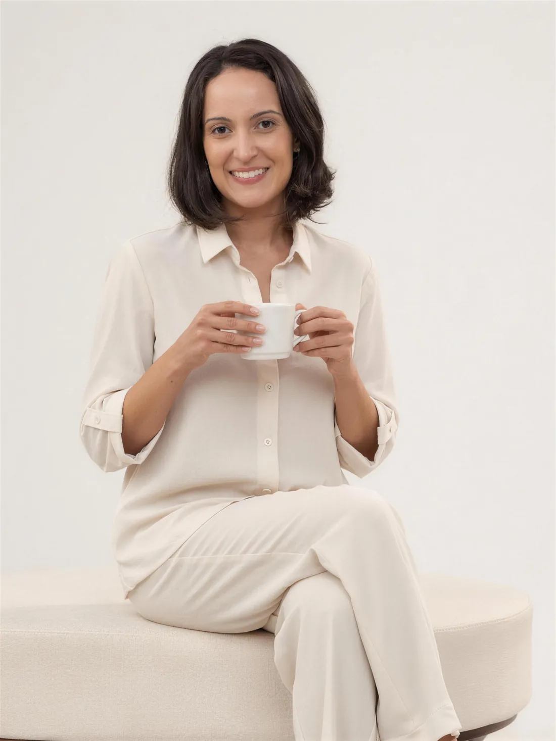 Dra. Viviane Vendramini sorrindo com uma xícara de café no consultório